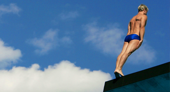 Diver on tiptoe at the edge of a diving board, preparing to jump